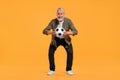 Happy senior sports fan with soccer ball on yellow background