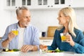 Happy Senior Spouses Chatting And Drinking Orange Juice During Breakfast In Kitchen Royalty Free Stock Photo