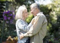 Happy senior spouses dancing in garden on warm spring day, looking at each other and smiling, resting together outdoors Royalty Free Stock Photo