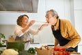 Happy senior spouses tasting food, woman giving her husband to try soup, cooking lunch together in kitchen interior Royalty Free Stock Photo