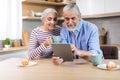 Happy Senior Spouses Using Digital Tablet Together While Having Breakfast In Kitchen Royalty Free Stock Photo