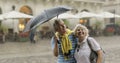 Happy senior tourists stand downtown and enjoy the rainy weather in Lviv Royalty Free Stock Photo