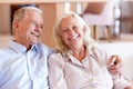 Happy senior white couple sitting at home embracing, front view, close up