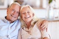 Happy senior white couple sitting at home embracing and smiling to camera, front view, close up Royalty Free Stock Photo