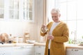 Happy senior woman pouring water into glass in kitchen