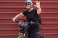 Happy senior woman cyclist in outdoor excursion close to a red metal panel. Elderly people ejoying healthy lifestyle Royalty Free Stock Photo