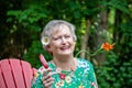 Happy stylish senior woman sitting in garden with popcycle Royalty Free Stock Photo