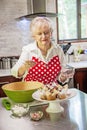 Happy senior woman decorating cupcakes in a bright modern kitchen Royalty Free Stock Photo