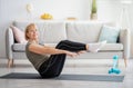 Happy senior woman doing abs exercises on yoga mat at home. Stay fit and healthy during covid quarantine