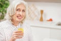 Happy senior woman drinking juice in kitchen Royalty Free Stock Photo