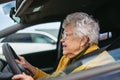 Happy senior woman driving car alone, enjoying car ride. Safe driving for elderly adults, older driver safety.