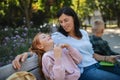 Happy senior woman with grandchildren sitting on bench and having snack outdoors in park. Royalty Free Stock Photo