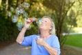 Happy senior woman having fun blowing bubbles Royalty Free Stock Photo