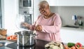 Happy senior woman having fun preparing lunch in modern kitchen - Hispanic Mother cooking for the family Royalty Free Stock Photo