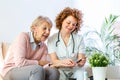 Happy senior woman having her blood sugar measured in a nursing home by her caregiver. Happy nurse measuring blood sugar of a