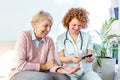 Happy senior woman having her blood sugar measured in a nursing home by her caregiver. Happy nurse measuring blood sugar of a