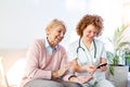 Happy senior woman having her blood sugar measured in a nursing home by her caregiver. Happy nurse measuring blood sugar of a