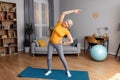 Happy senior woman having workout at home, cheerful aged lady in sportswear exercising on yoga mat Royalty Free Stock Photo