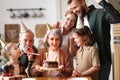 Happy senior woman holding cake with burning candles while celebrating birthday with big lovely family Royalty Free Stock Photo