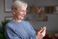 Happy senior woman holding phone, texting an sms to her children