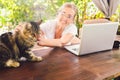 Happy senior woman with home cat use wireless headphones working online with laptop computer outdoor Royalty Free Stock Photo