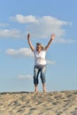 Portrait of happy senior woman jumping on sandy hill Royalty Free Stock Photo