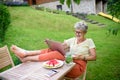 Happy senior woman with laptop working outdoors in garden, home office concept. Royalty Free Stock Photo