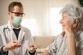 Happy senior woman listening as her doctor is explaining therapy details during house call visit