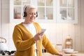 Happy senior woman listening to music on smartphone at home Royalty Free Stock Photo