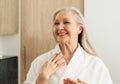 Happy senior woman looking at her reflection in the mirror in morning in the bathroom Royalty Free Stock Photo