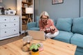 Happy senior woman making online payments of bill using laptop. Smiling mature woman shopping online with credit card. Pensioner Royalty Free Stock Photo