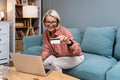 Happy senior woman making online payments of bill using laptop. Smiling mature woman shopping online with credit card. Pensioner Royalty Free Stock Photo