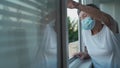 Happy senior woman in mask waves to family from window hospital. Masked elderly female glad that children came visit her Royalty Free Stock Photo