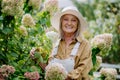 Happy senior woman posing in the flower garden.