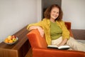 Happy senior woman reading book while relaxing on couch at home Royalty Free Stock Photo