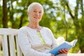 Happy senior woman reading book at summer park Royalty Free Stock Photo