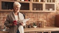 Happy Senior Woman Reading Newspaper And Drinking Hot Tea In Kitchen Royalty Free Stock Photo