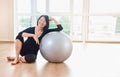 Happy senior woman resting after exercise with gray exercise ball