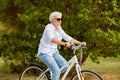 Happy senior woman riding bicycle at summer park Royalty Free Stock Photo