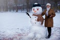 Happy senior woman sculpt and hug a big real snowman Royalty Free Stock Photo