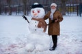 Happy senior woman sculpt a big snowman in winter Royalty Free Stock Photo