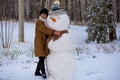 Happy senior woman sculpt and hug a big real snowman Royalty Free Stock Photo