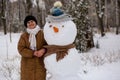 Happy senior woman sculpt and hug a big real snowman Royalty Free Stock Photo