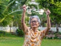 A happy senior woman showing clenching fists excited for success with arms raised celebrating victory smiling while standing Royalty Free Stock Photo