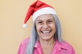 Happy senior woman smiling on camera wearing Santa Clause hat during Christmas time - Focus on face Royalty Free Stock Photo