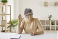 Happy senior woman smiling and waving hello during video call or online conference Royalty Free Stock Photo