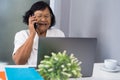 Happy senior woman talking on mobile phone and working on laptop Royalty Free Stock Photo