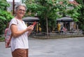 Happy senior woman walking in the city holding her mobile phone. Elderly female enjoying tech and social Royalty Free Stock Photo