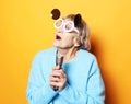 Happy senior woman wearing blue sweater and big sunglasses singing with microphone Royalty Free Stock Photo