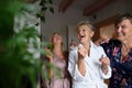 Happy senior women friends in bathrobes having fun indoors at home, selfcare concept.